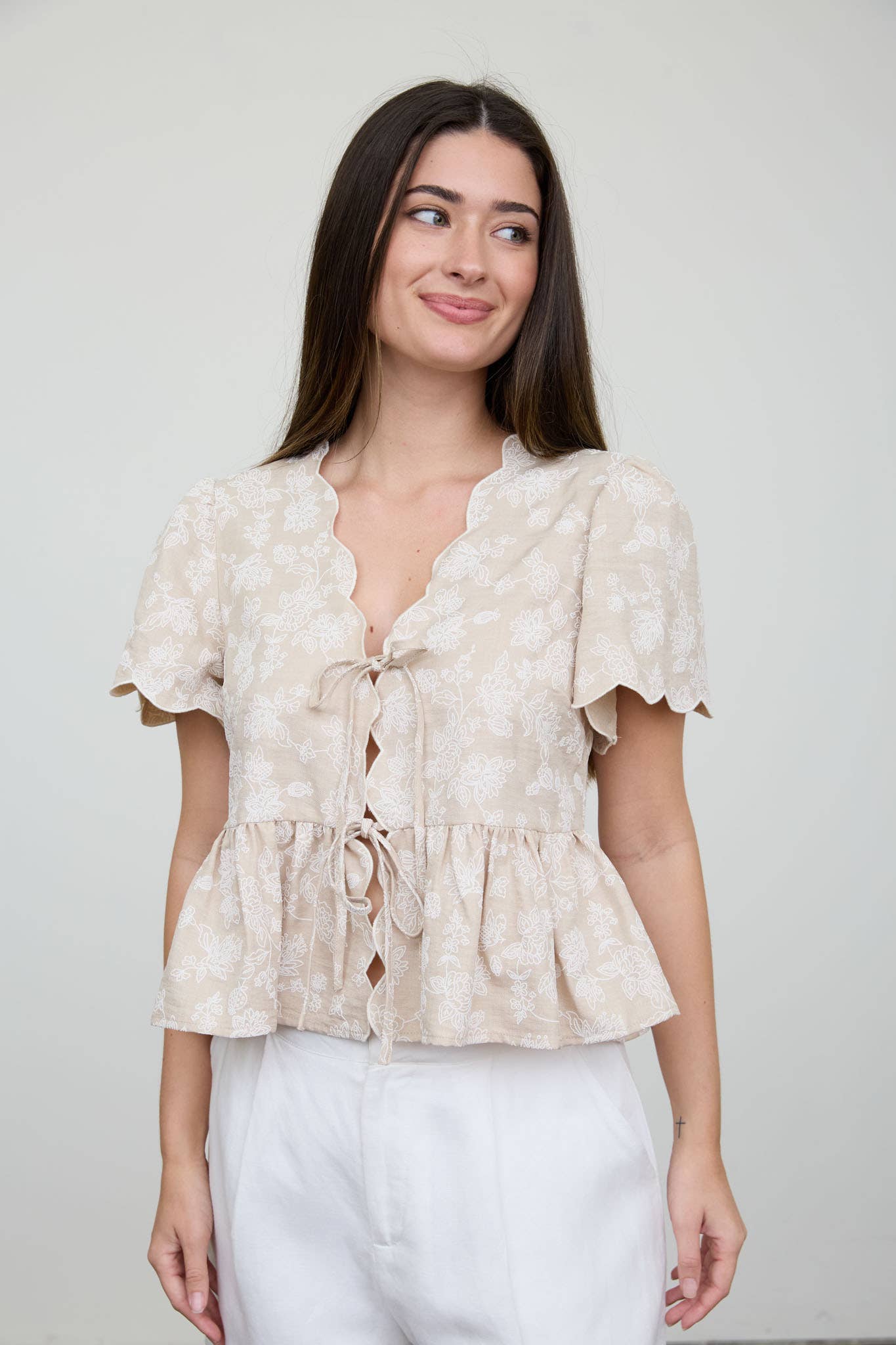 Top peplum con bordado floral, lazo delantero y bajo festoneado