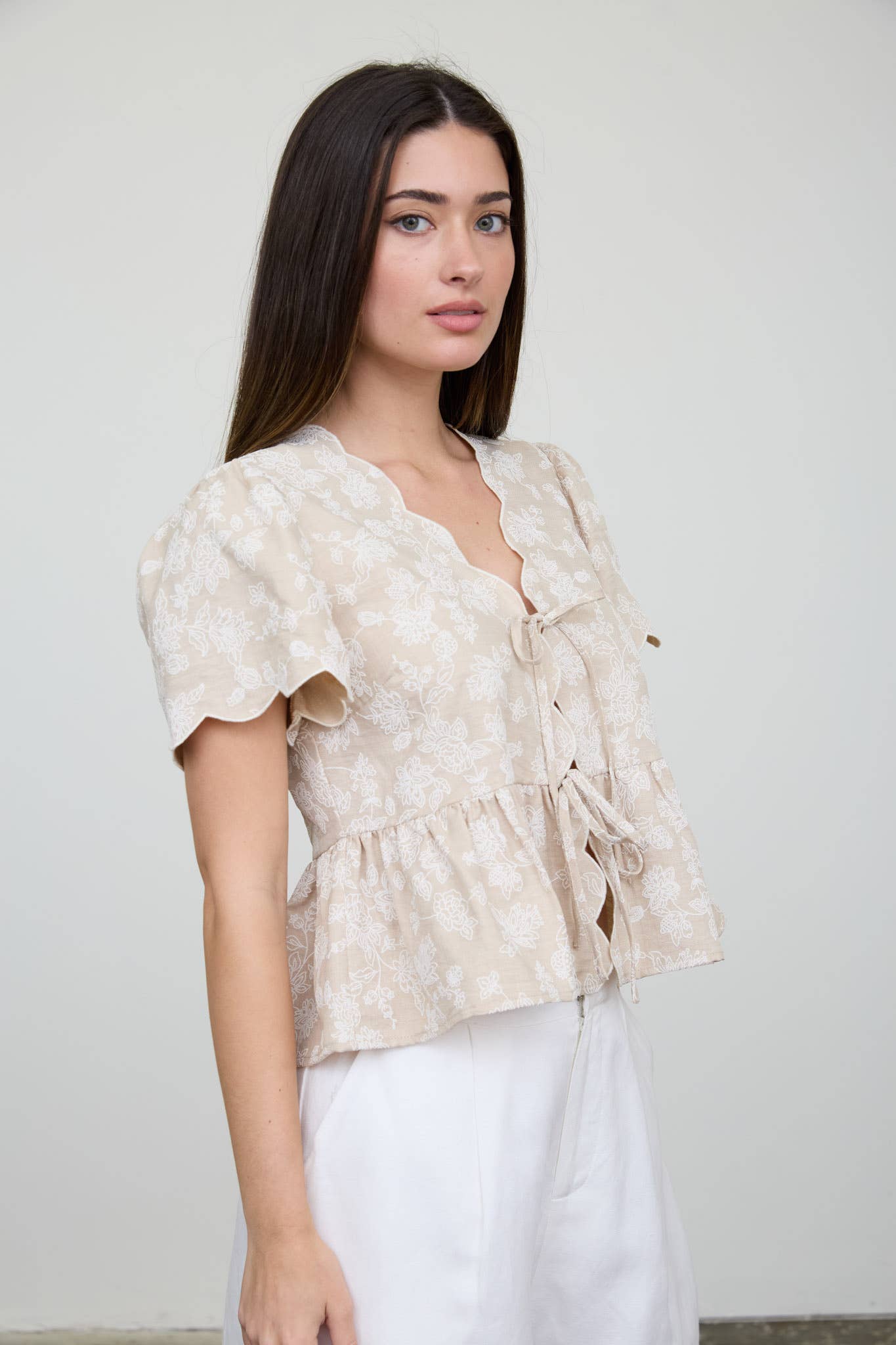 Top peplum con bordado floral, lazo delantero y bajo festoneado