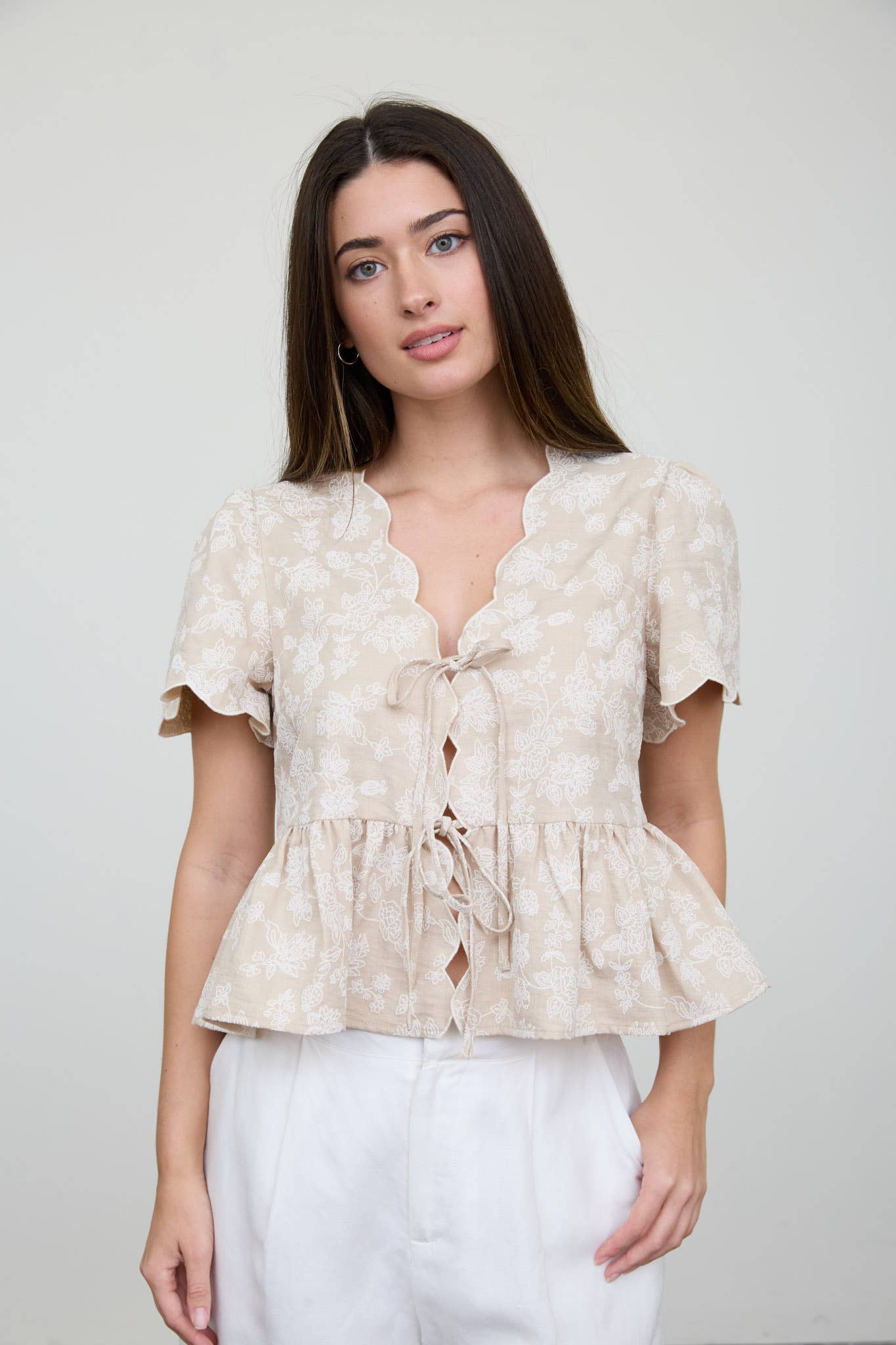 Top peplum con bordado floral, lazo delantero y bajo festoneado