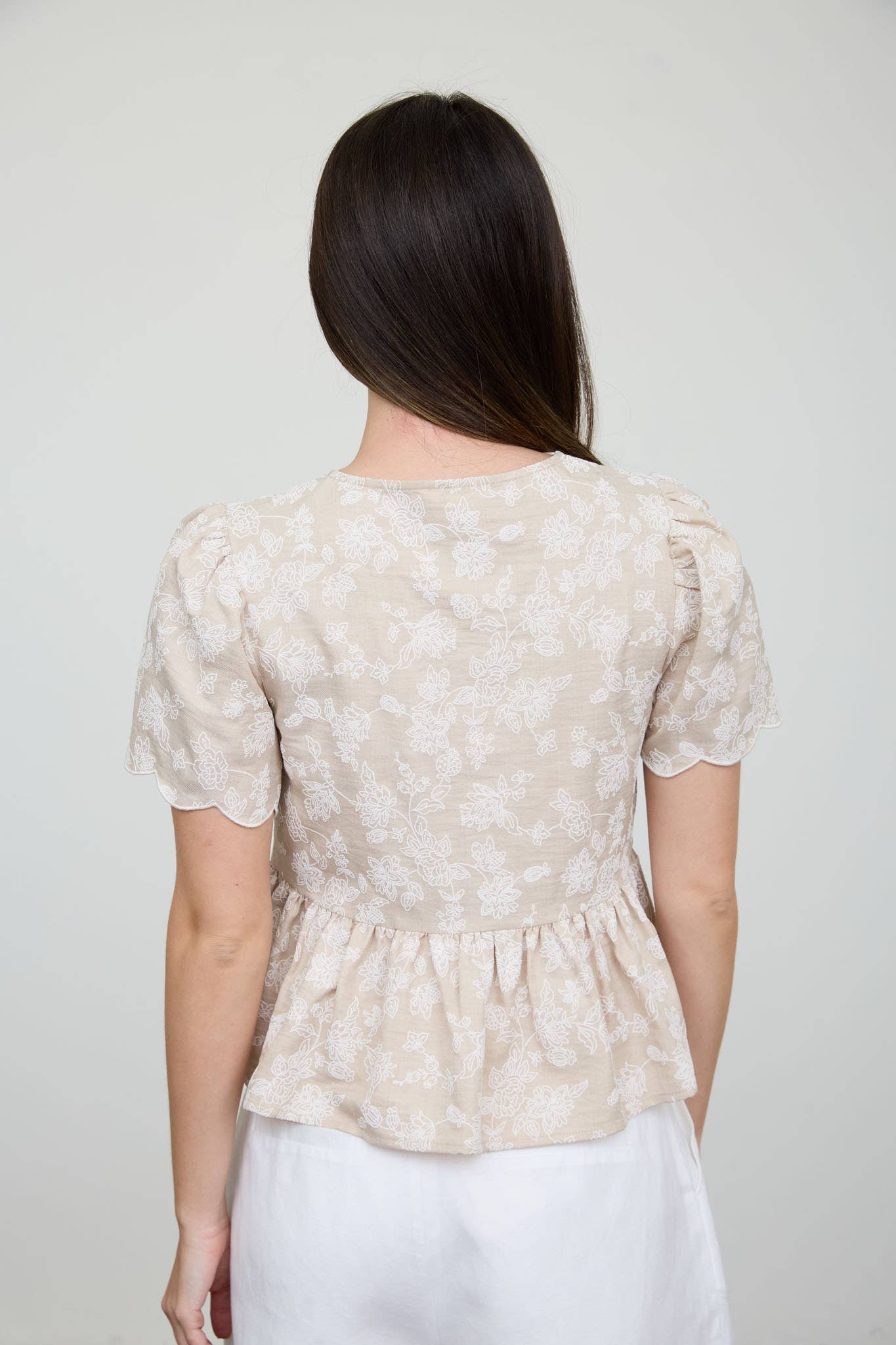 Top peplum con bordado floral, lazo delantero y bajo festoneado