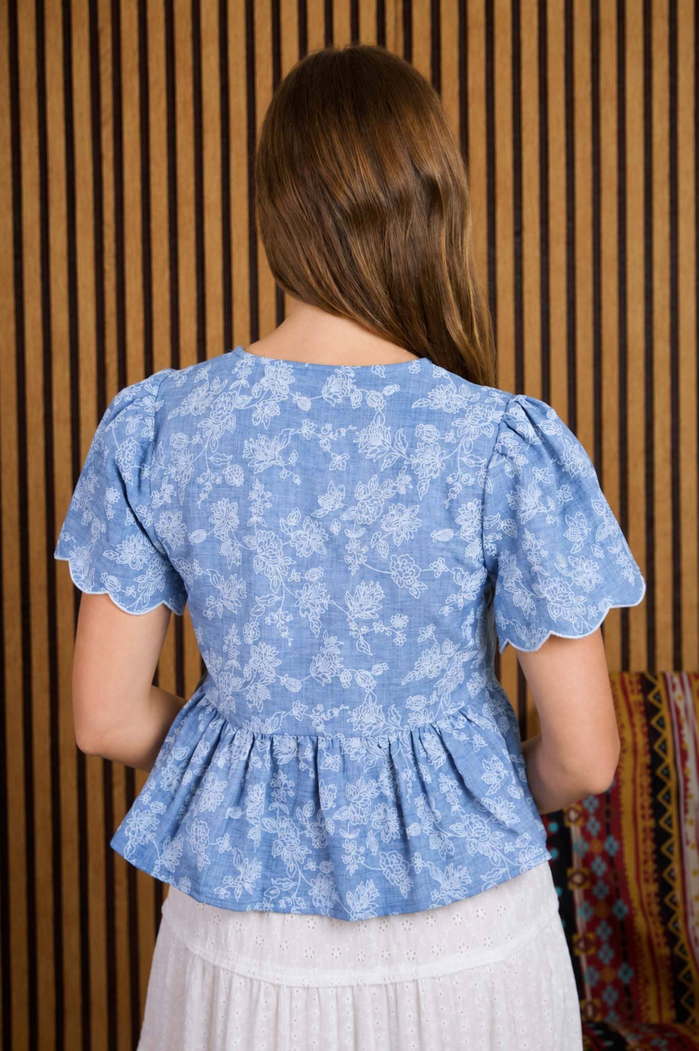 Top peplum con bordado floral, lazo delantero y bajo festoneado
